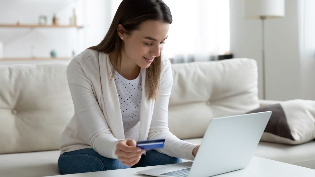 Person holding credit card while looking at laptop.