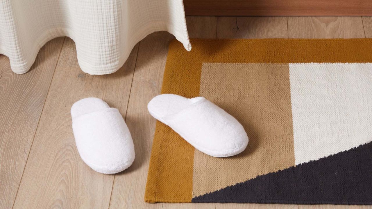 A pair of white slippers on a wooden floor.