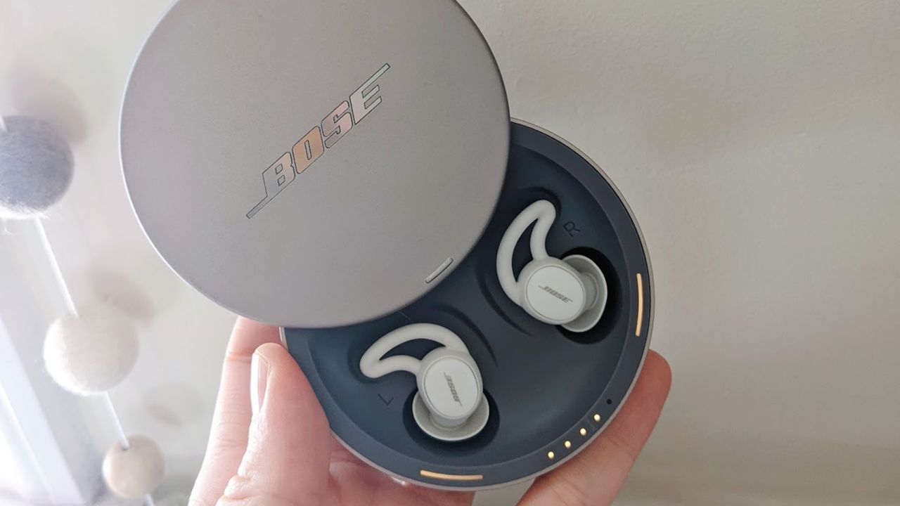 Person holding a round case with Bose Sleep Buds inside.