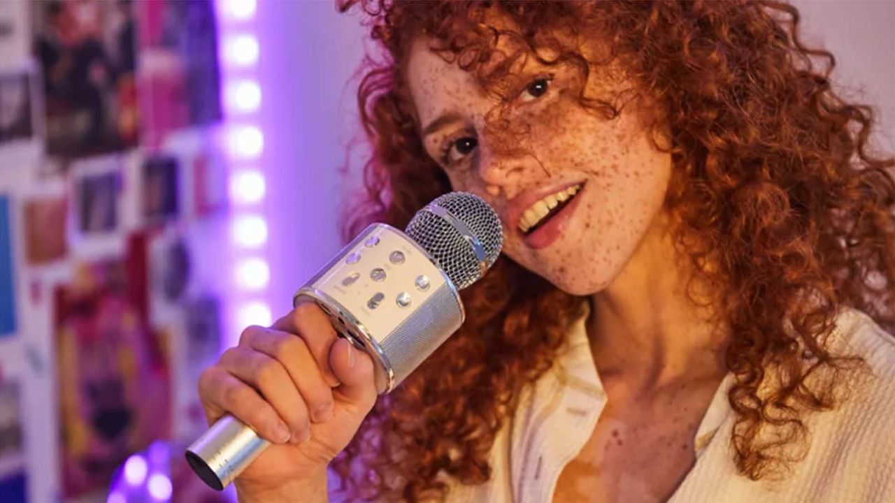 Person with curly red hair holding a karaoke mic.