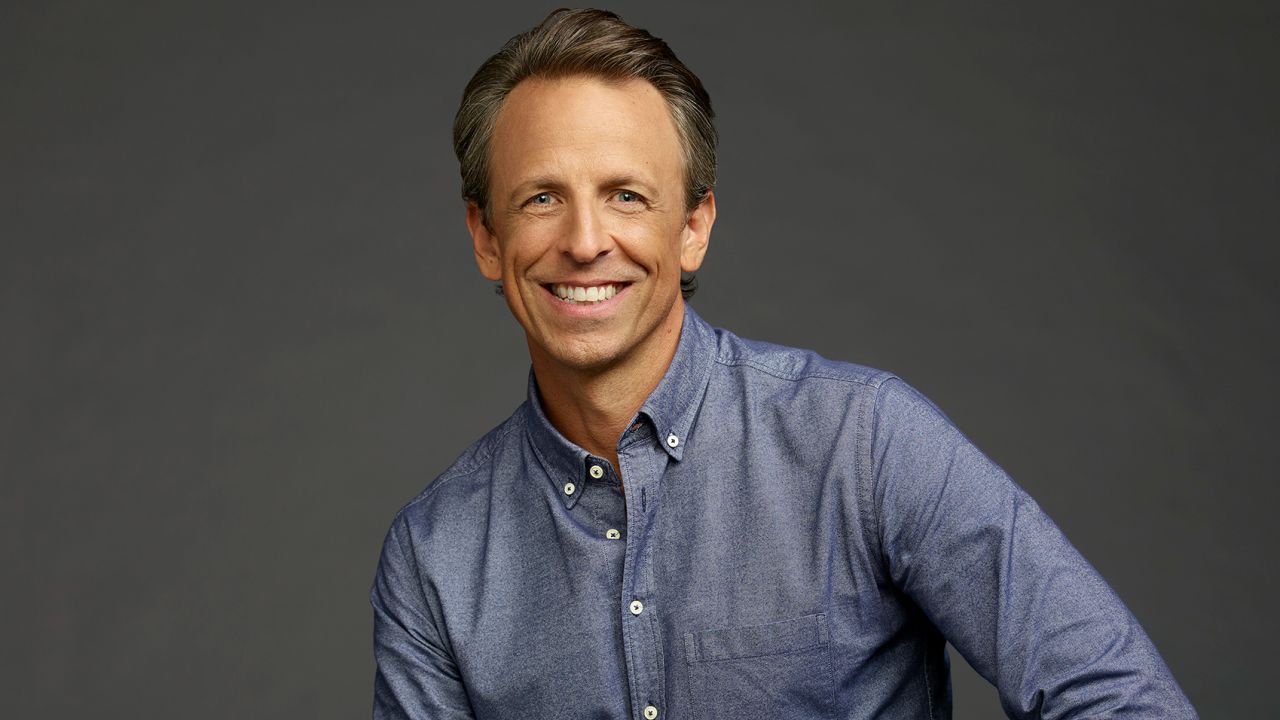 Seth Meyers smiling while wearing blue button-up shirt.