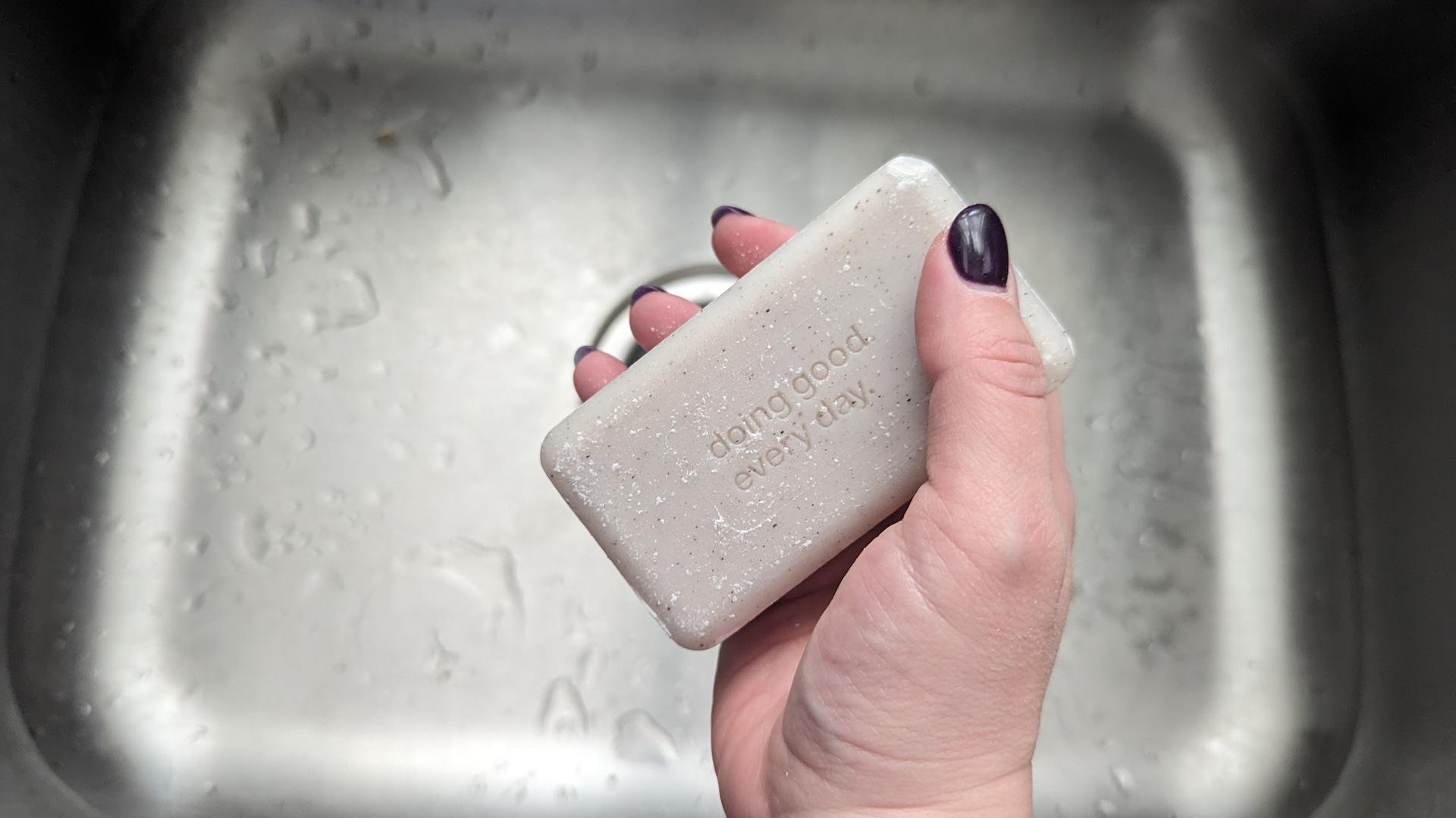 Person holding a bar of soap over a sink